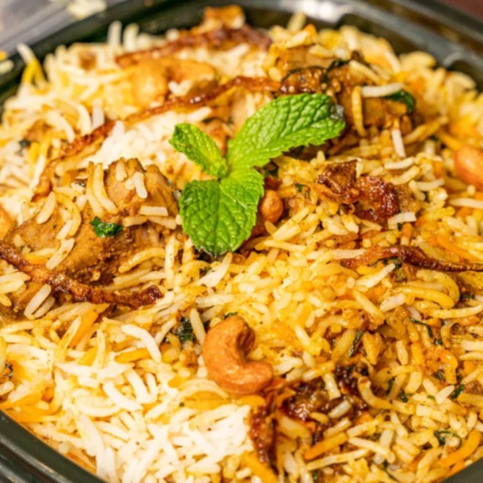 Close-up of Bombay Corner's chicken biryani, garnished with fresh mint and cashews.